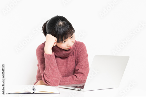 ノートパソコンを使いながら悩んでいる女性