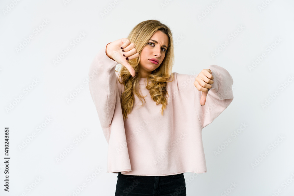 Young caucasian blonde woman showing thumb down and expressing dislike. Young caucasian blonde woman showing thumb down and expressing dislike.