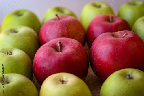 Green and red apples stand on a wooden surface