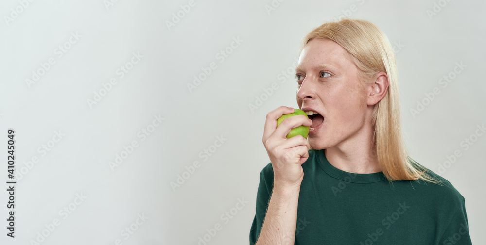 Handsome young caucasian man biting green juicy apple