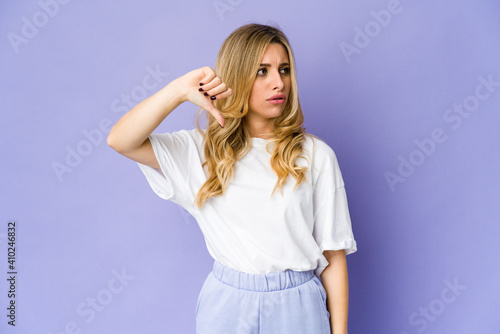 Young caucasian blonde woman showing thumb down and expressing dislike.
