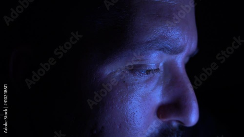 Young male is working late during the night. Close up side shot of a man concentrated on his work on the computer. Home office and staying late concept.
