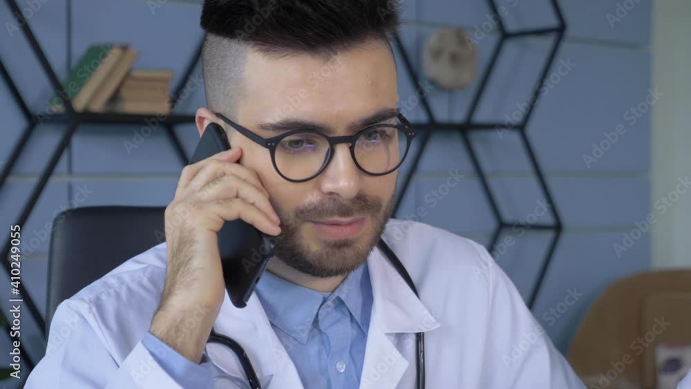 Close Up of A European Male Doctor Talking on the Phone Is in the Hospital Office Close Up of A European Male Doctor Talking on the Phone Is in the Hospital Office