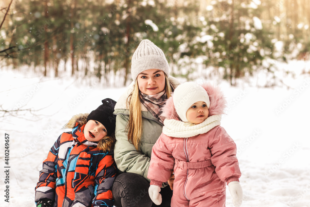 Young mother with a little son and a daughter in the park in winter. Motherhood and childhood Young mother with a little son and a daughter in the park in winter. Motherhood and childhood
