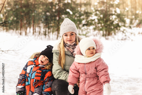 Young mother with a little son and a daughter in the park in winter. Motherhood and childhood