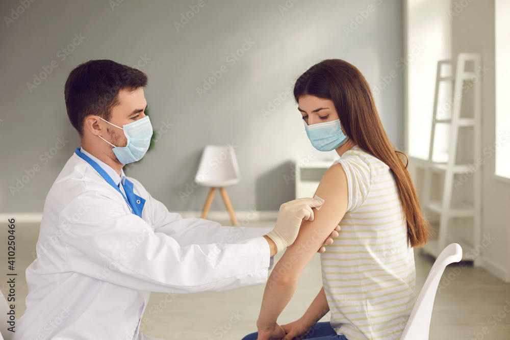 Side view doctor applies the patch to the patient's arm after injecting her with a seasonal flu or infection vaccine. Concept of healthcare, vaccination and medical services. Side view doctor applies the patch to the patient's arm after injecting her with a seasonal flu or infection vaccine. Concept of healthcare, vaccination and medical services.
