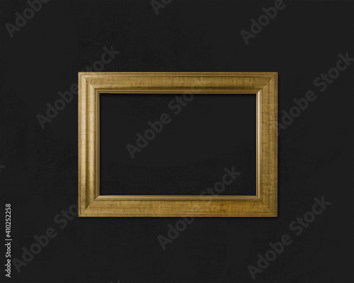 Horizontal golden baguette art frame on dark background. Materials for artists and photographers. Close-up color photo. © KOSIM