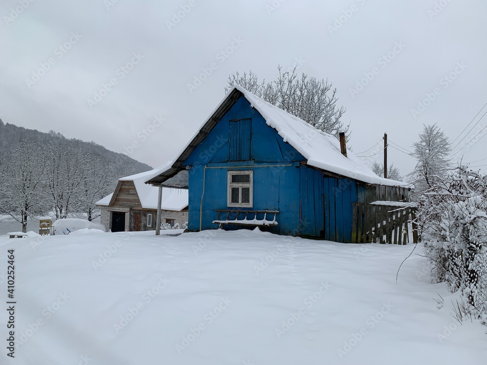 Wooden house in the village in winter. An old wooden building by the forest. Village house in the mountains. Wooden house in the village in winter. An old wooden building by the forest. Village house in the mountains.