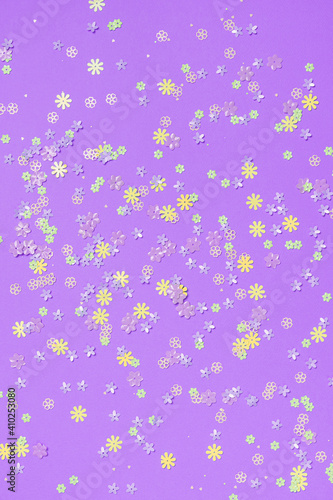 Festive purple background with colorful flowers. Multi-colored small artificial flowers. Flat lay, top view.