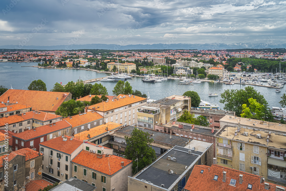 Obraz premium Drone or birds eye view on orange tiled roofs and cityscape of Zadar. Bay or marina with moored yachts and boats, Croatia