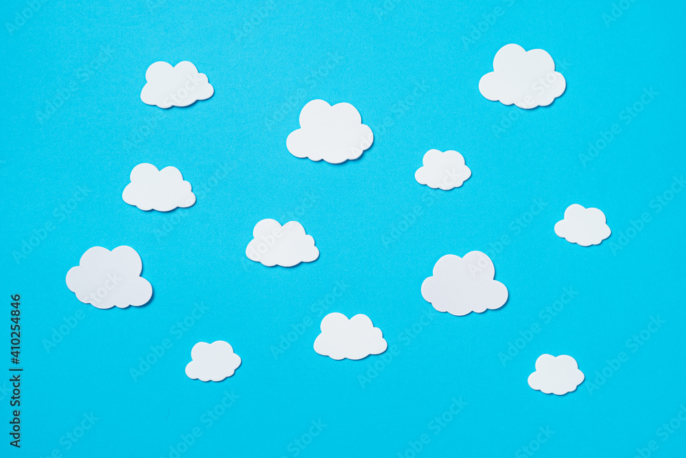 Elements in shape of white clouds on paper blue background. Greeting card design. Flat lay. Top view