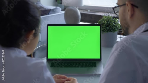 Close up of Two Doctors A Woman and a Man Looking at a Computer Screen with a Green Screen Chromakey or Laptop Is in the Hospital Office