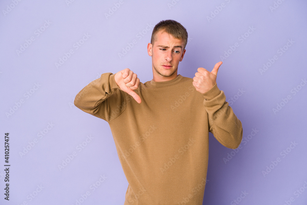 Fototapeta premium Young caucasian handsome man showing thumbs up and thumbs down, difficult choose concept