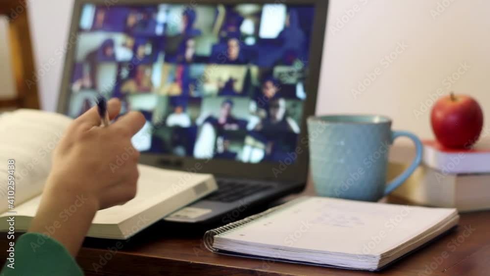 Student taking an online class with his arm raised to ask a question