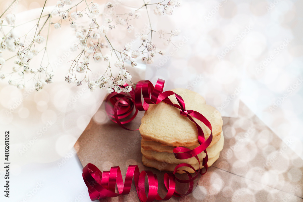 heart-shaped cookies with a red ribbon and a white bouquet of flowers.Space for text. heart-shaped cookies with a red ribbon and a white bouquet of flowers.Space for text.