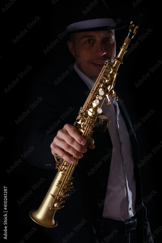 Naklejka premium soprano saxophone in the hands of a guy on a black background