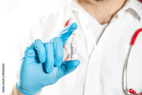 A medical worker hand in protective glove holding COVID-19 vaccine bottle.