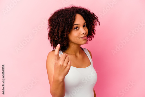 Young african american mixed race woman isolated pointing with finger at you as if inviting come closer.