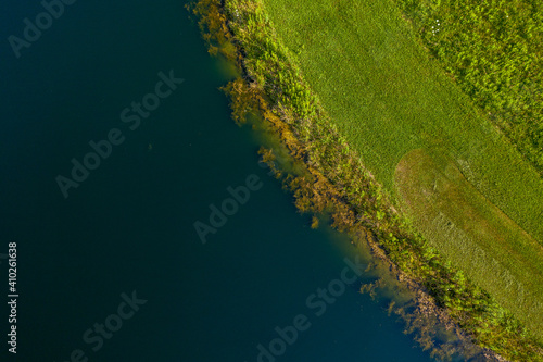 Top Down Aerial View Of Water Meeting Grassland 