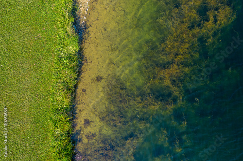 Top Down Aerial View Of Land Meeting Murky Water.