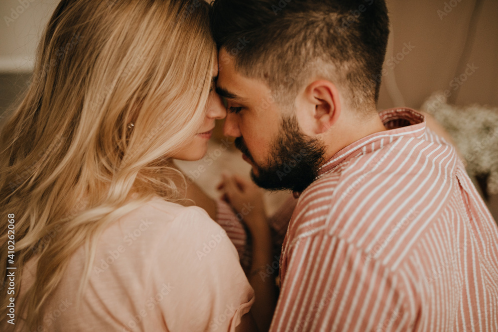 Lovely couple in romantic mood poses for close-up portrait. Brunette guy and blonde girl are touching noses Lovely couple in romantic mood poses for close-up portrait. Brunette guy and blonde girl are touching noses