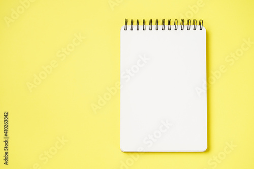 School notebook on a paper yellow background, spiral notepad and craft cardboard pen