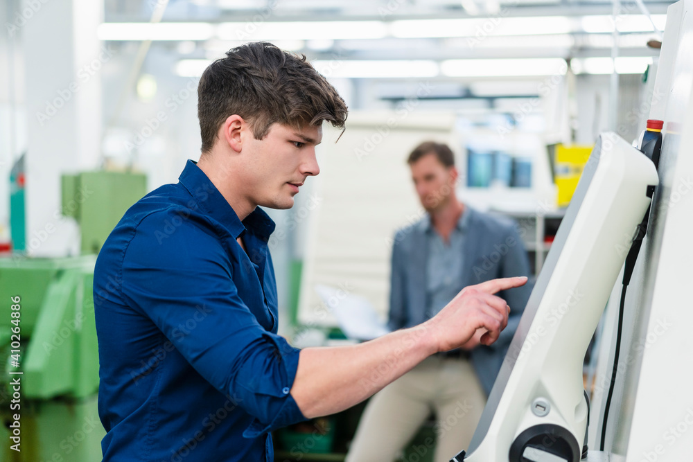 Male engineer operating machinery equipment while working in factory Male engineer operating machinery equipment while working in factory