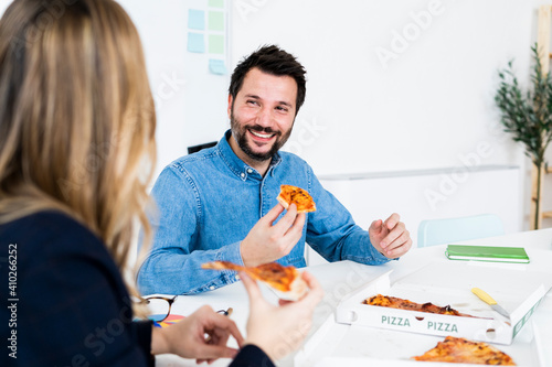 Business people eating pizza and talking in office during break photo