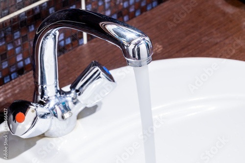 domestic bathroom faucet with pouring water. low water pressure. leaky tap concept. plumbing conceptual