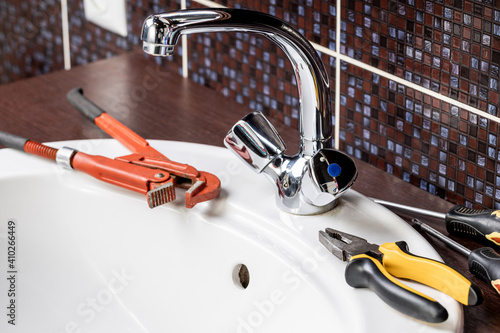 plumbing faucet repair concept. plumber using wrench tool and pliers to adjusting tap leak at bathroom. diy plumber conceptual