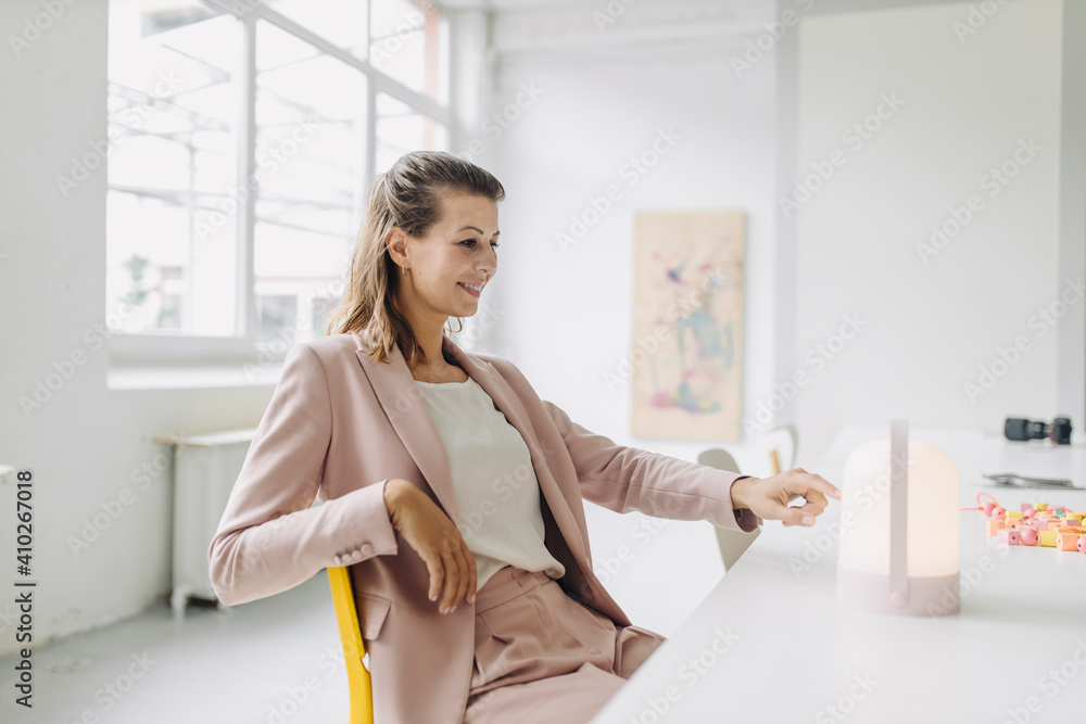 Smiling businesswoman looking at lantern in office Smiling businesswoman looking at lantern in office