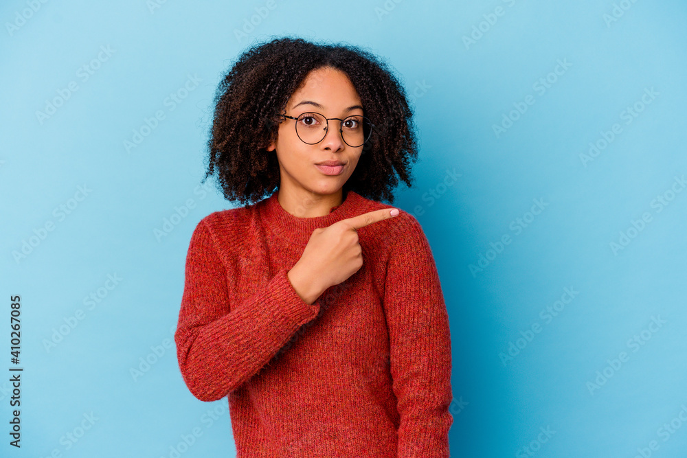 Fototapeta premium Young african american mixed race woman isolated smiling and pointing aside, showing something at blank space.