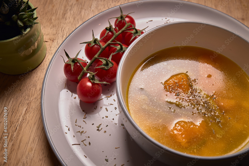 Vegetable soup or broth with pumpkin and chickpeas in a bowl. fine spreading herbs. solid wood background. Healthy, vegan and diet food. tasty recipe Vegetable soup or broth with pumpkin and chickpeas in a bowl. fine spreading herbs. solid wood background. Healthy, vegan and diet food. tasty recipe