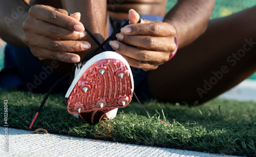 Sportswoman tying shoelace of spikes running shoes in sports court photo