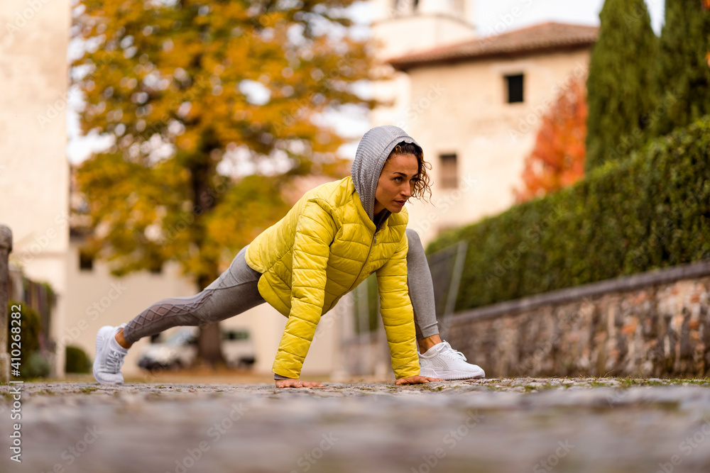 Woman looking away while exercising on footpath Woman looking away while exercising on footpath
