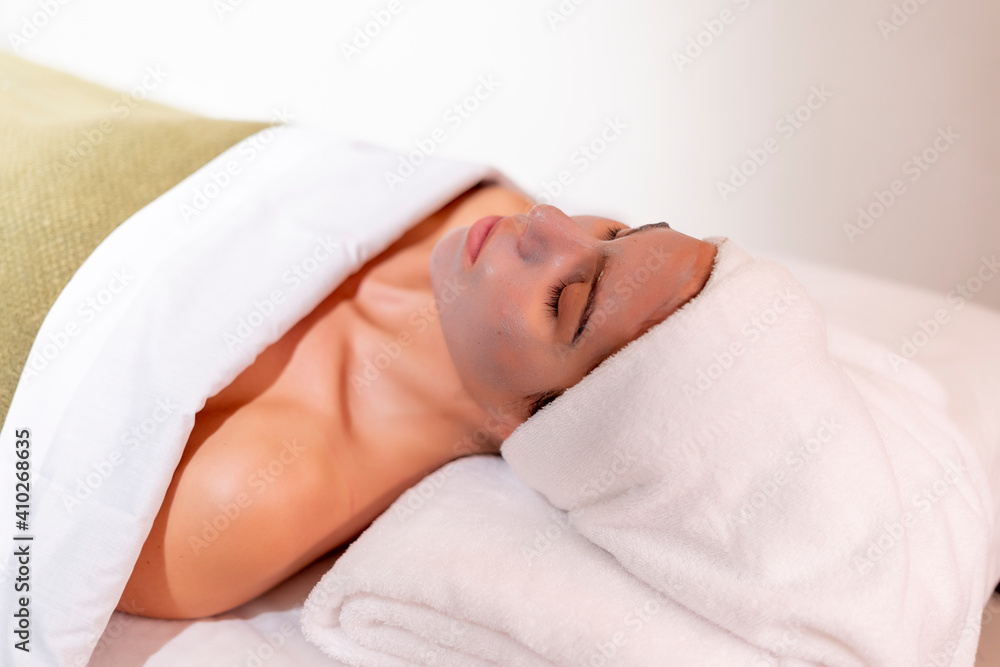 Young female customer lying on massage table at health spa Young female customer lying on massage table at health spa