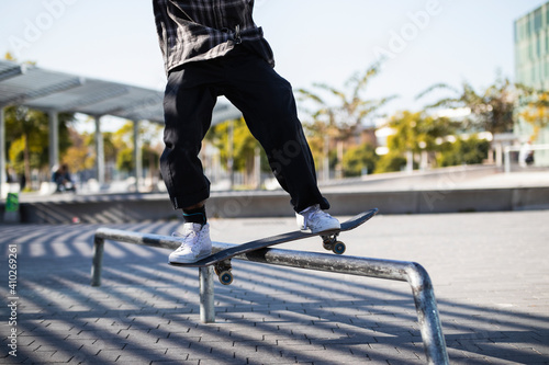 Man balancing while standing with skateboard over hurdle at skateboard park photo