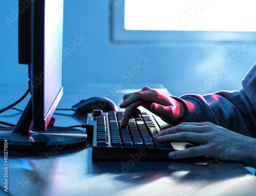 Hands of teenage boy breaching data from computer on desk photo