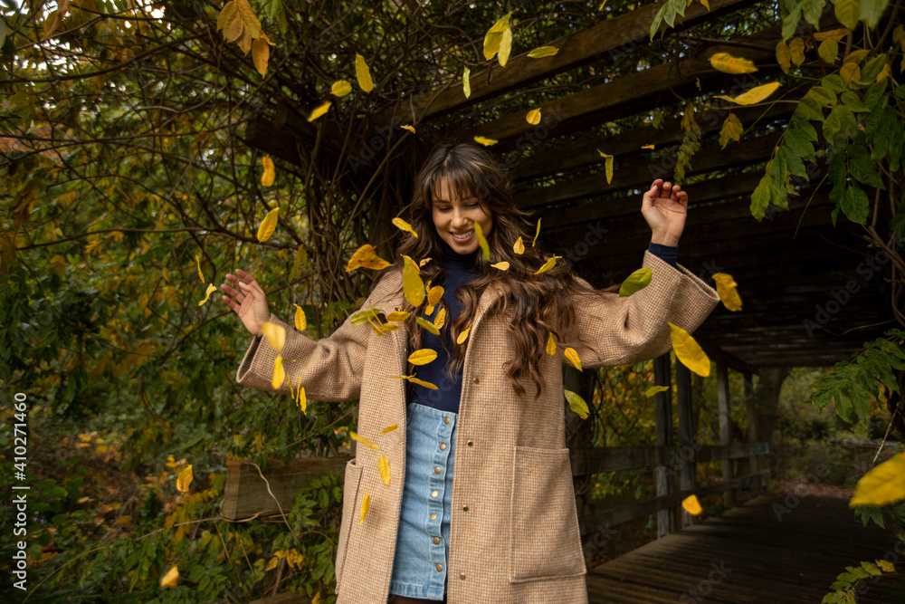 Happy woman with arms raised standing in falling leafs at public park during autumn Happy woman with arms raised standing in falling leafs at public park during autumn