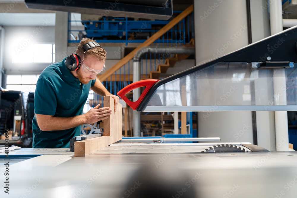 Carpenter cutting plank on circular saw in production hall Carpenter cutting plank on circular saw in production hall
