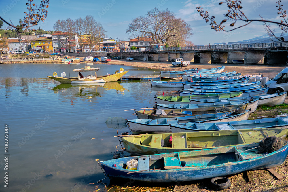 Many colorful boats and canoes on the coast of Lake Uluabat and parking of cars near the lake. Bursa. Golyazi. Turkey. 22.01.2021.
