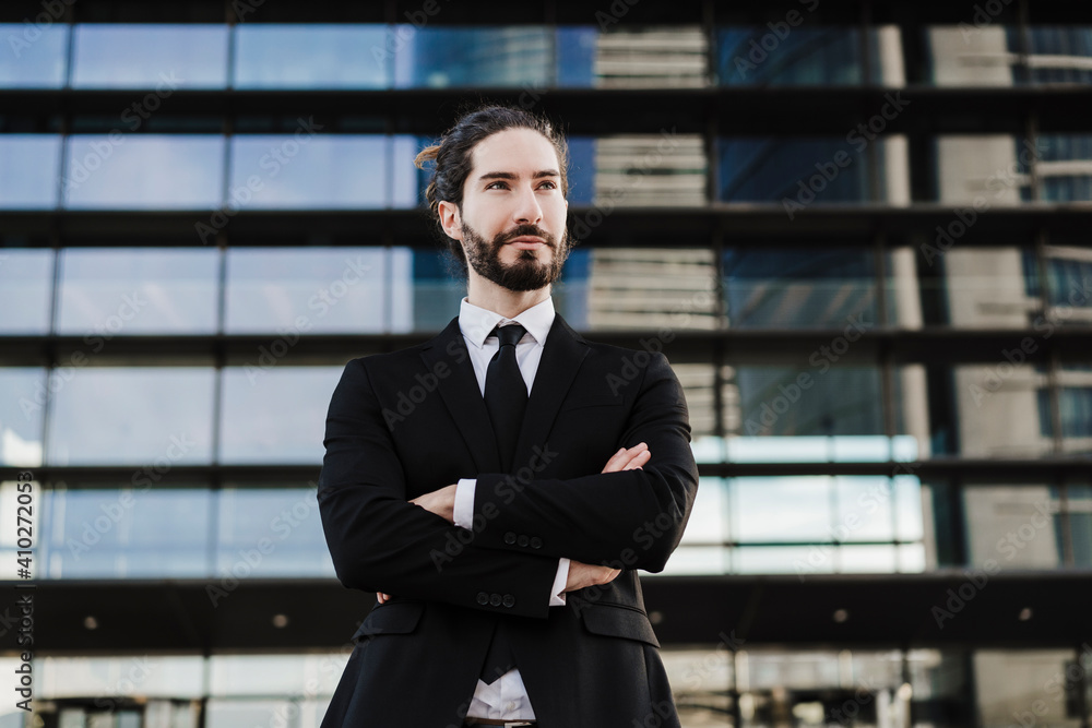 Confident young entrepreneur standing with arms crossed against building Confident young entrepreneur standing with arms crossed against building