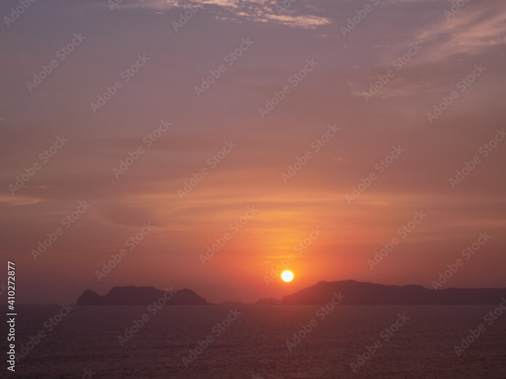 Fototapeta premium Atardecer frente al mar con cielo de colores en Lima, Perú. El Sol ocultándose entre las islas San Lorenzo y El Frontón.