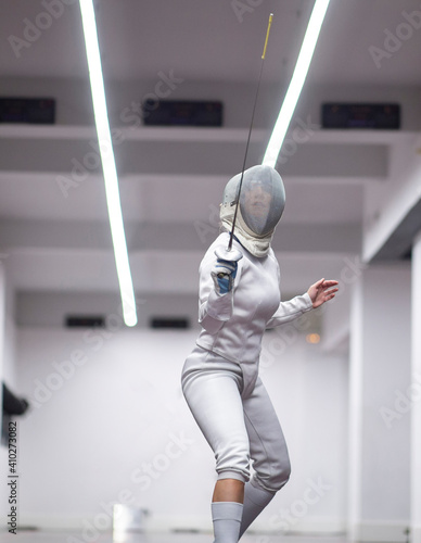 Woman¬†in fencing outfit practicing at gym