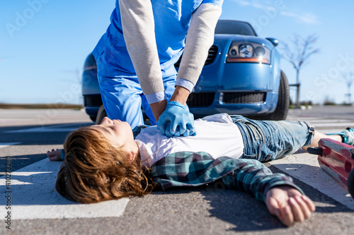 Rescue worker using giving CPR to victim lying on road after car accident photo