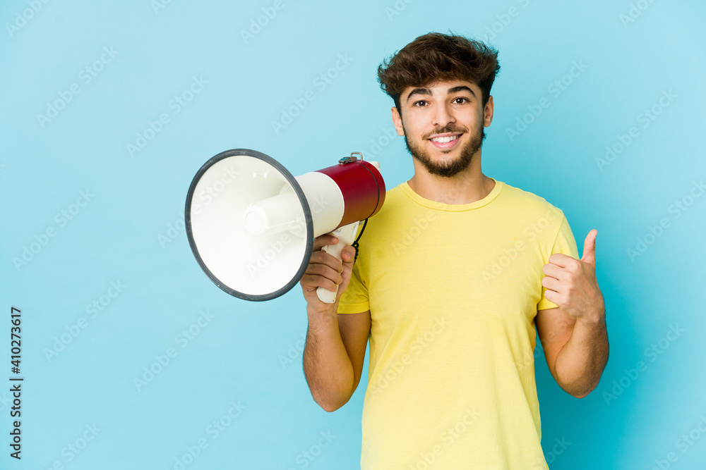 Young arab man holding a megaphone smiling and raising thumb up Young arab man holding a megaphone smiling and raising thumb up