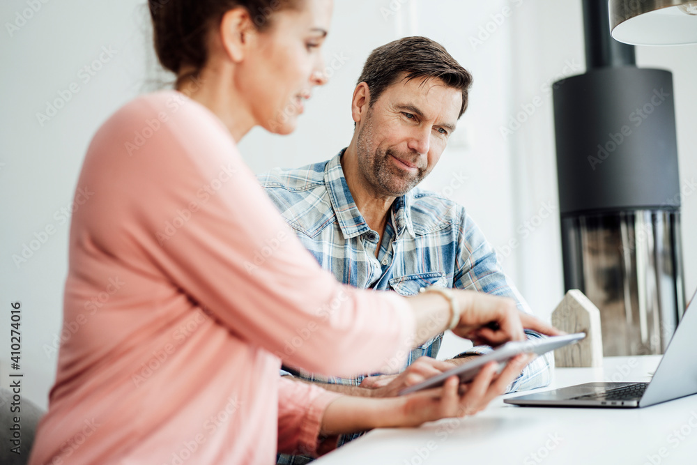 Mature business couple discussing while working on table at home office Mature business couple discussing while working on table at home office