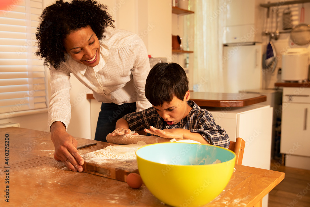 Smiling mother looking at son preparing food on table in kitchen Smiling mother looking at son preparing food on table in kitchen