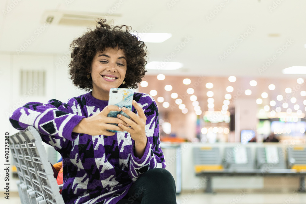 Smiling woman using smart phone while sitting at airport Smiling woman using smart phone while sitting at airport