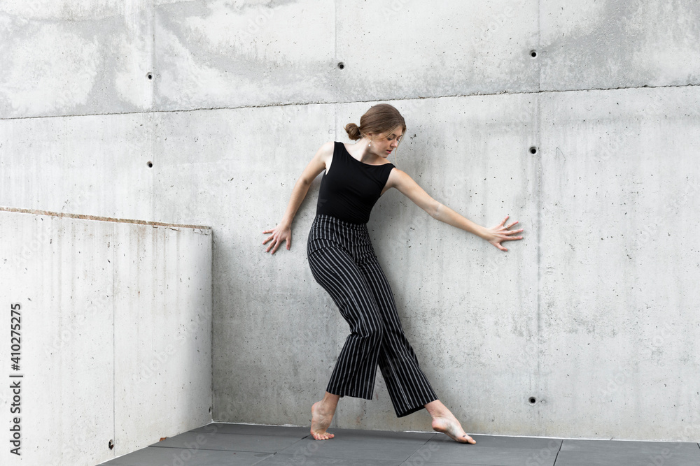 Dancer in black striped pants in front of concrete wall Dancer in black striped pants in front of concrete wall